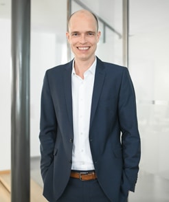 Sebastian Schmitz, Immobilienmakler für Gewerbeimmobilien steht im modernen Foyer von Schneider Immobilien auf der Bahnstraße 1 in Ratingen