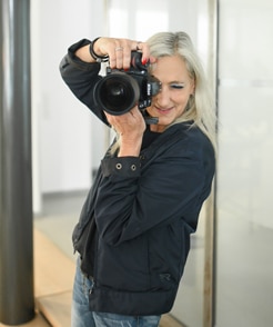 Anja Schultz schaut für Schneider Immobilien durch die professionelle Kamera
