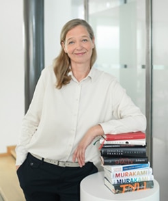 Jasmin Sieg verantwortet bei Schneider Immobilien GmbH PR und Marketing und zeigt ihr Hobby Lesen mit einem Stapel Lieblingsbüchern