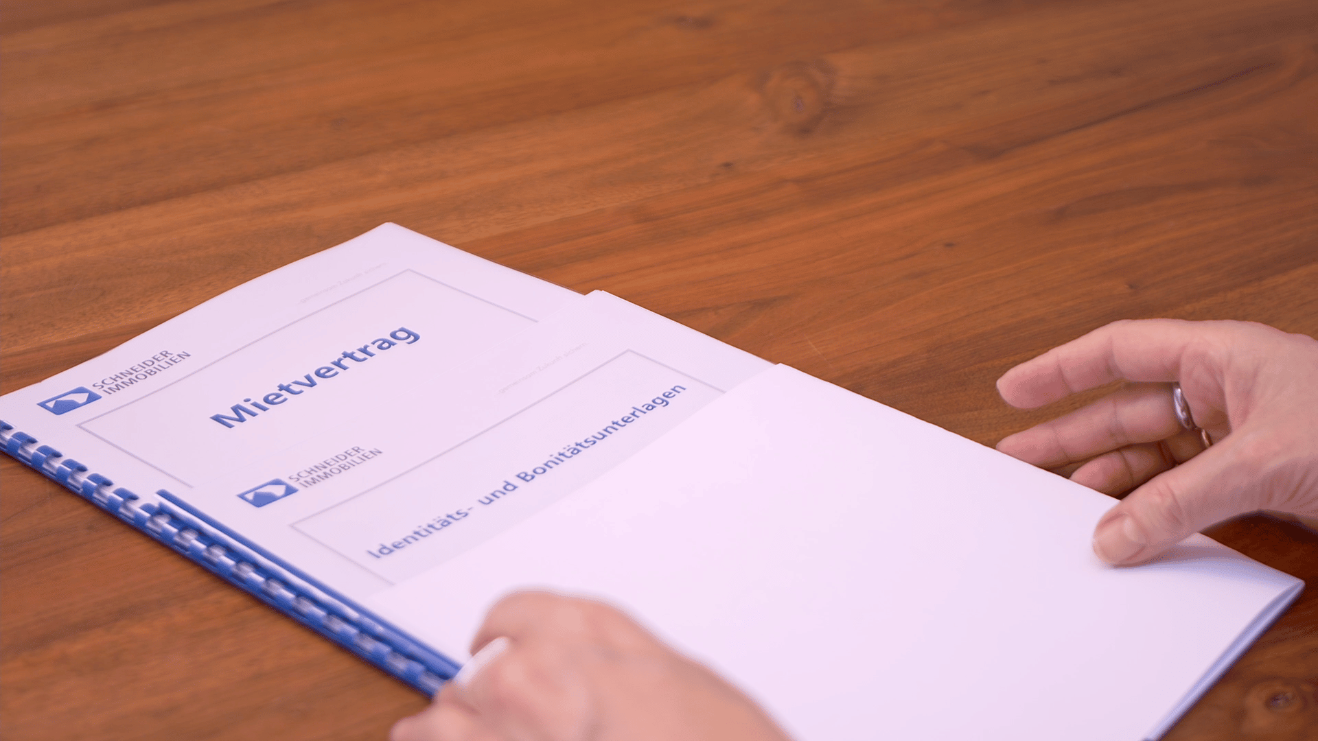 Bonitätsunterlagen und ein Mietvertrag liegen für den Eigentümer zur Übergabe auf dem Tisch von Schneider Immobilien