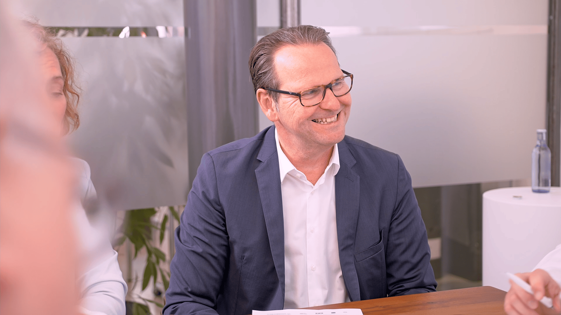 Das Bild zeigt Stefan Schneider, den Geschaeftsfuehrer und Inhaber von Schneider Immobilien sympathisch und lächend in einem Beratungsgespräch im Besprechungsraum des Büros in Ratingen.